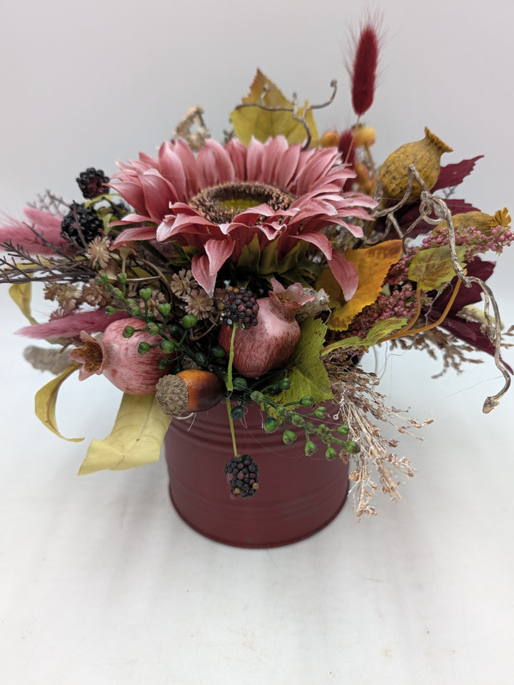 Herbstgesteck mit rosa Sonnenblume, Granatäpfeln und Brombeeren im dunkelroten Metalltopf, Draufsicht