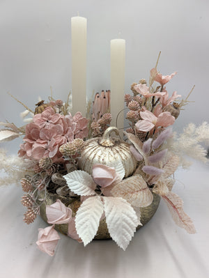 Herbstgesteck mit weißem Kürbis, rosa Hortensien, Rosenknospen und zwei cremefarbenen Stabkerzen in goldener Schale