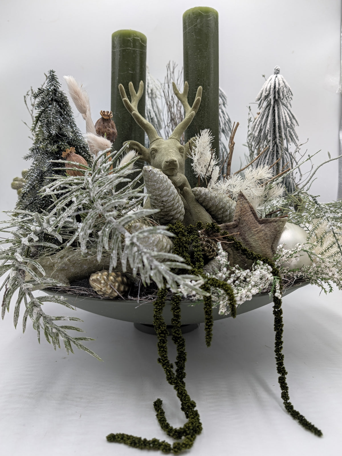 Seitenansicht des Wintergestecks auf Fußschale mit Rindenstern, silbernen Kugeln und herabhängenden grünen Fruchtständen