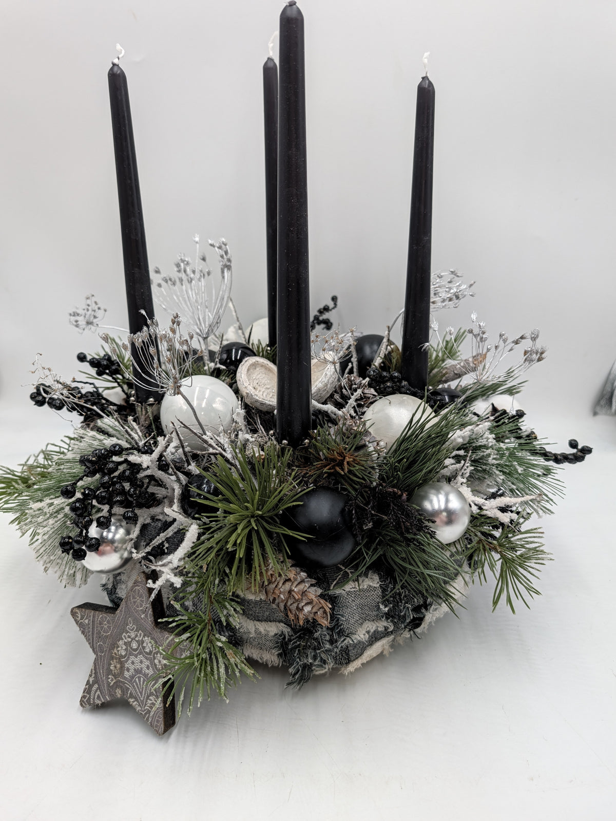 Adventskranz mit vier schwarzen Stabkerzen, weißen und silbernen Kugeln, Kiefernzweigen und Holzstern