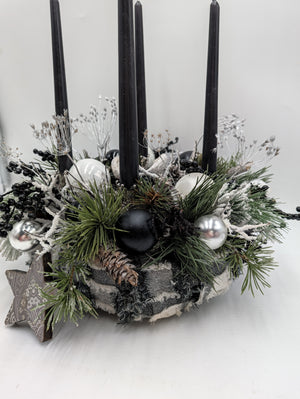 Adventskranz von der Seite: karierter Stoffrand, Zapfen, schwarze und silberne Kugeln zwischen grünen Zweigen