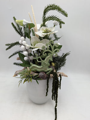 Wintergesteck im weißen Topf mit Christrosen, grünem Glitzerhirsch, weißen Beeren und hängendem Amarant