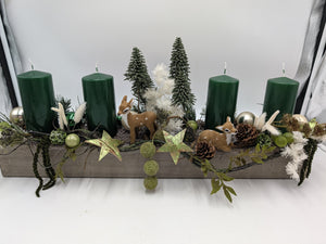 Adventsgesteck im Holzkasten mit vier grünen Kerzen, zwei Rehkitzen, Tannenbäumen, Zapfen und goldenen Sternen