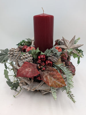 Adventsgesteck mit roter Stumpenkerze, weissen Zapfen, roten Kugeln und Holzstern auf Holzkranz