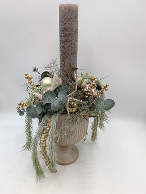 Weihnachtsgesteck mit hoher graubrauner Kerze, Eukalyptus, Gräsern und goldenen Kugeln in heller Amphorenvase