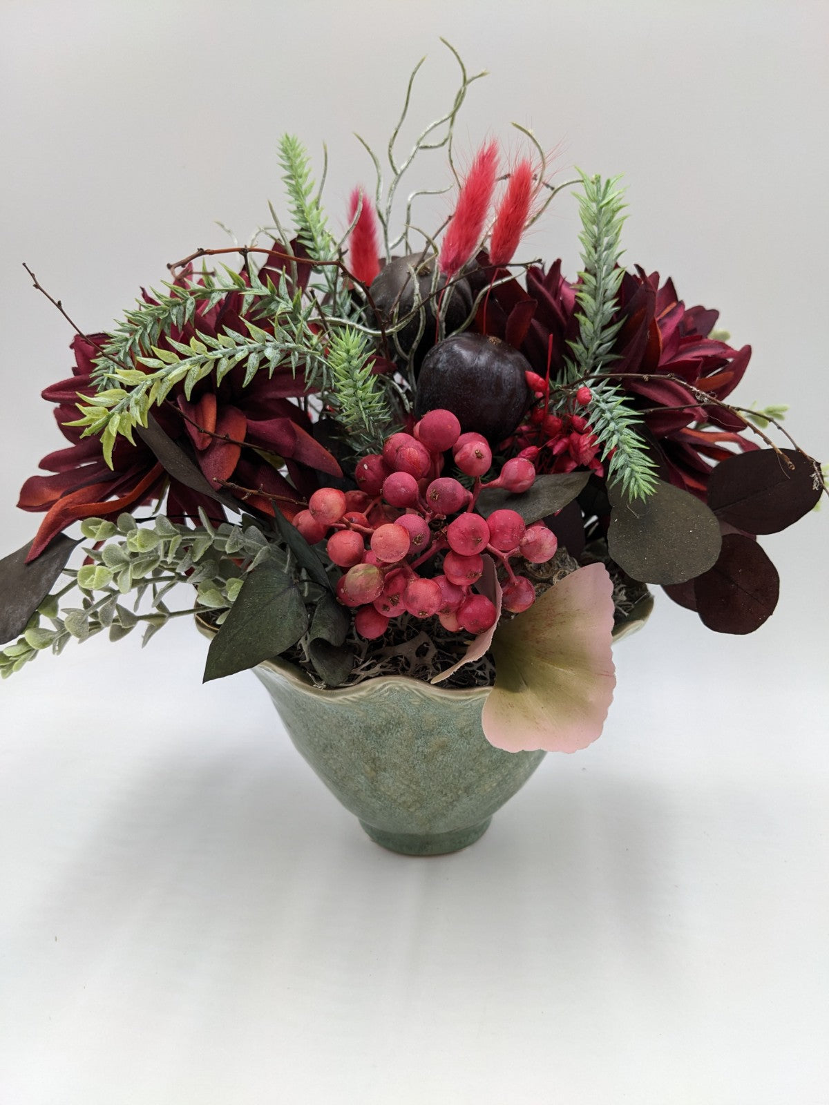 Herbstgesteck mit dunkelroten Dahlien, Feigen, rosaroten Beeren und Gräsern in grüner Keramikschale