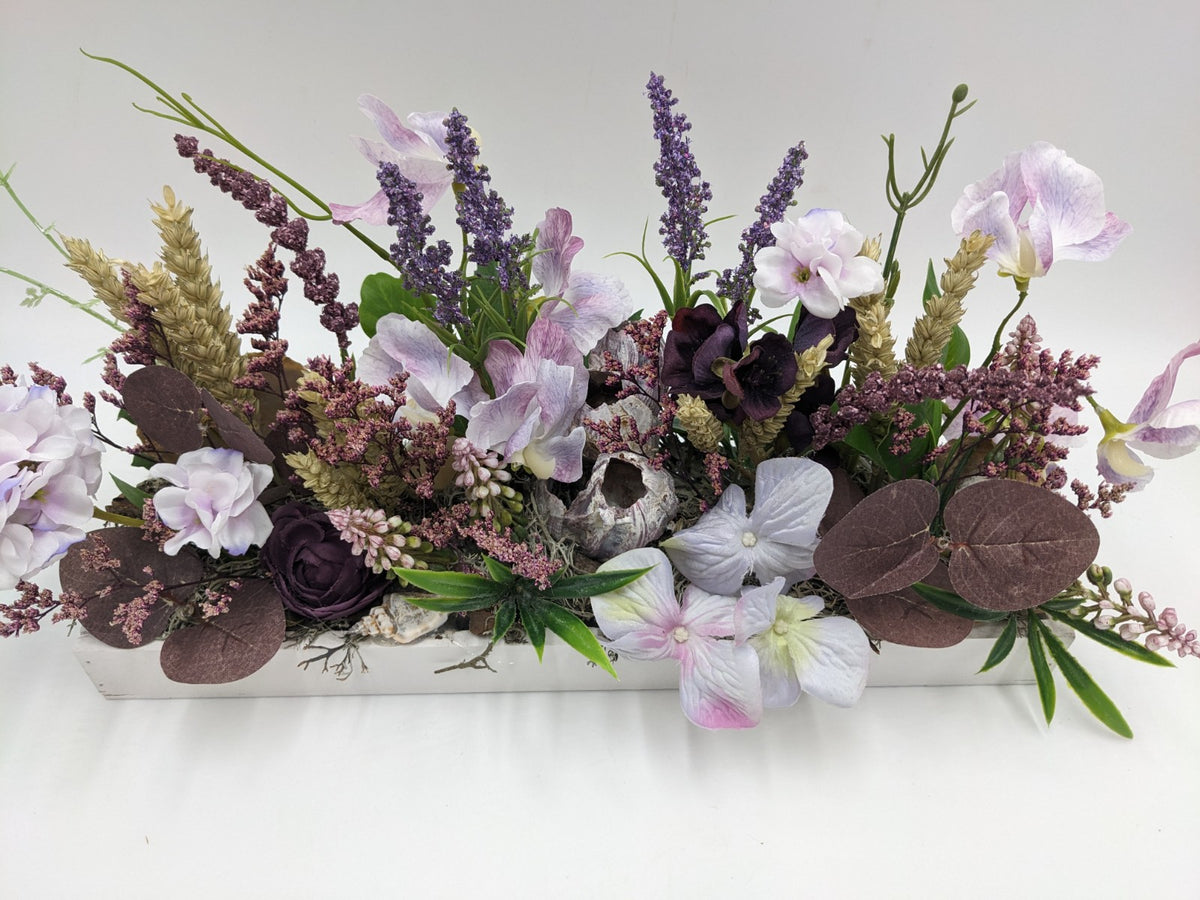 Sommergesteck aus der Nähe: helle Hyazinthen, dunkelviolette Rose, Lavendelrispen und braunviolette Blätter