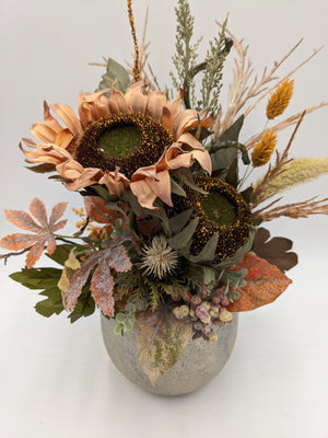 Nahaufnahme der apricotfarbenen Sonnenblumen mit dunklen Körben, heller Distel, roten Beeren und gelben Ähren