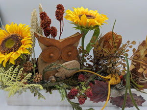 Nahaufnahme der Holzeule zwischen Sonnenblumen, Ähren, Zapfen, roten Beeren und weinroten Blättern