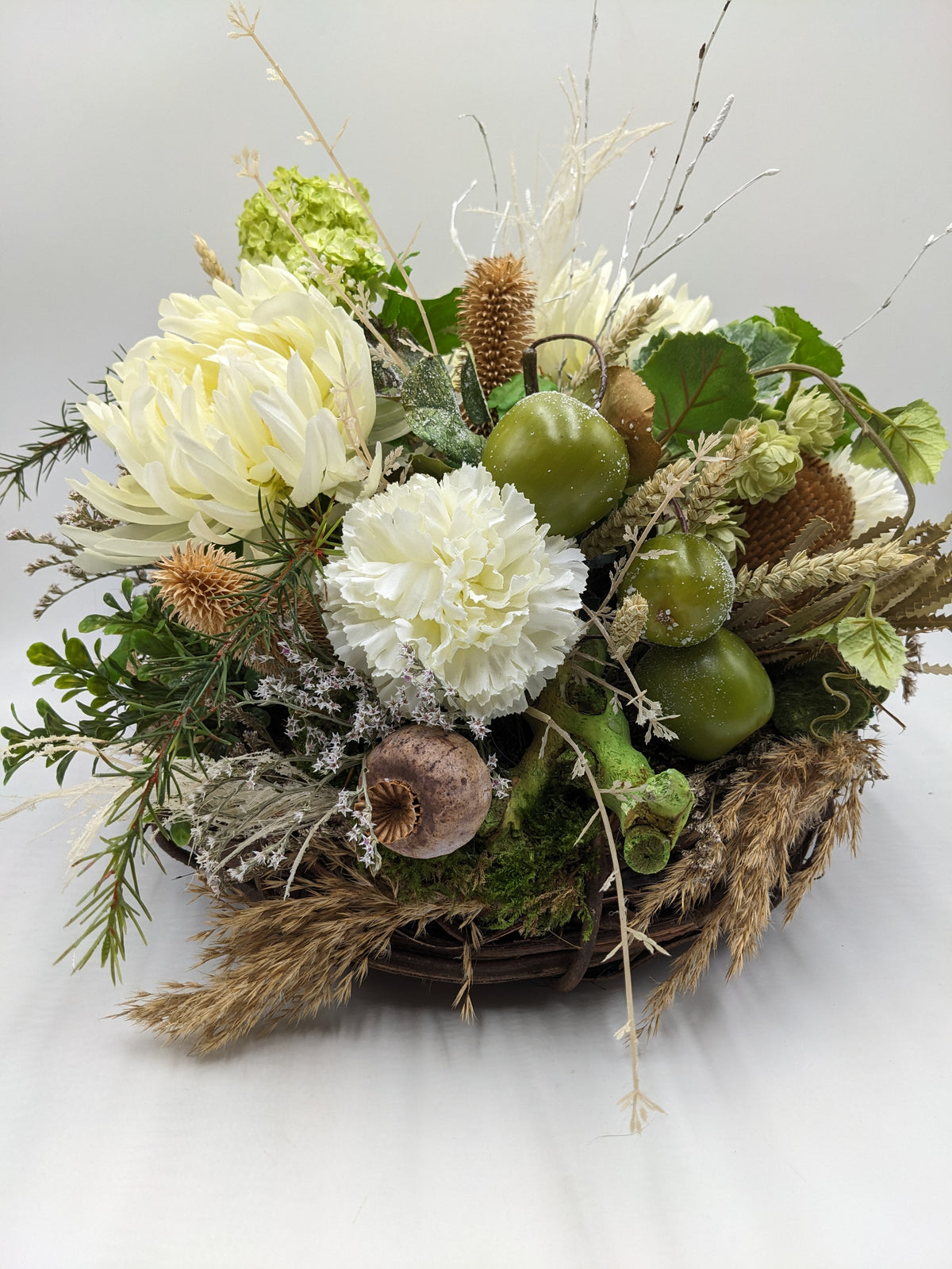 Herbstgesteck im Korb mit cremefarbener Chrysantheme, weißer Nelke, grünen Äpfeln, Hopfen und Ähren