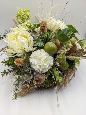 Herbstgesteck von schräg oben: grüner Schneeball, Mohnkapsel, Efeublätter, Moos und helle Gräser im Zweigkorb