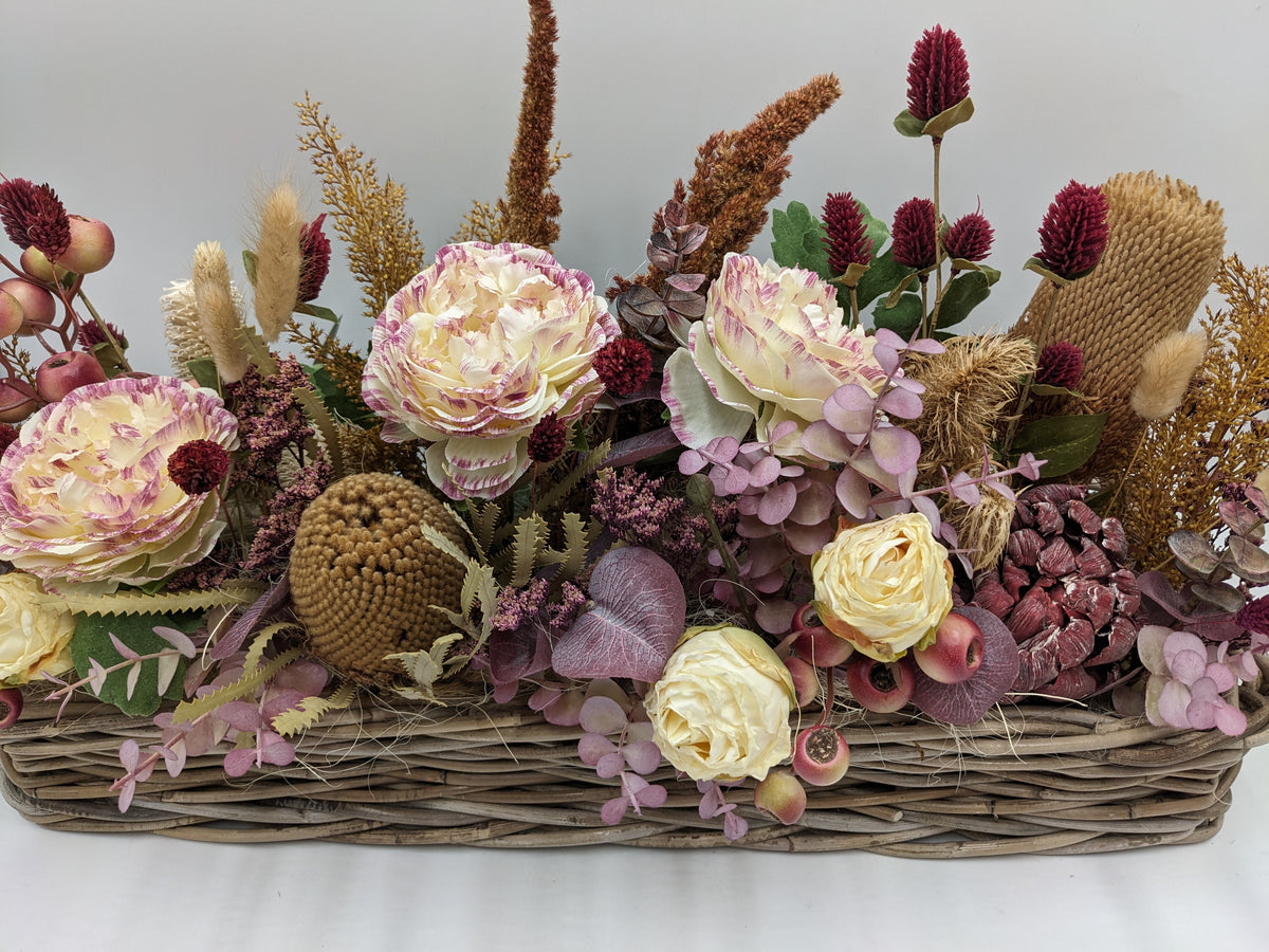 Nahaufnahme des Gestecks: Rosen mit rosa Rand, altrosa Eukalyptus, Zapfen, braune Ähren und Banksie-Blüte