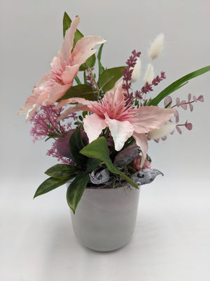 Herbstgesteck mit zwei rosa Clematisblüten, lila Rispen und weißen Gräsern in grauem Topf
