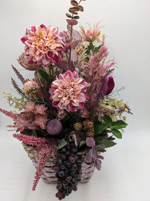 Herbstgesteck von vorn: Dahlien in Rosa und Apricot, lila Blüte, Hortensien, Beeren und Weintrauben im Korb