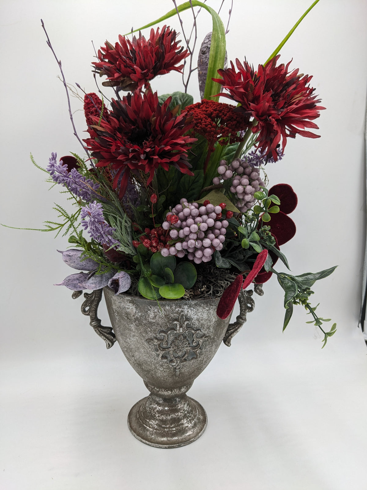 Herbstgesteck mit dunkelroten Chrysanthemen, fliederfarbenen Beeren und Lavendel in silbergrauem Pokal mit Henkeln