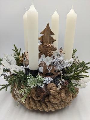 Adventsgesteck in Seilschale mit vier cremefarbenen Kerzen, Holztanne, Holzhaus und Schaukelpferd