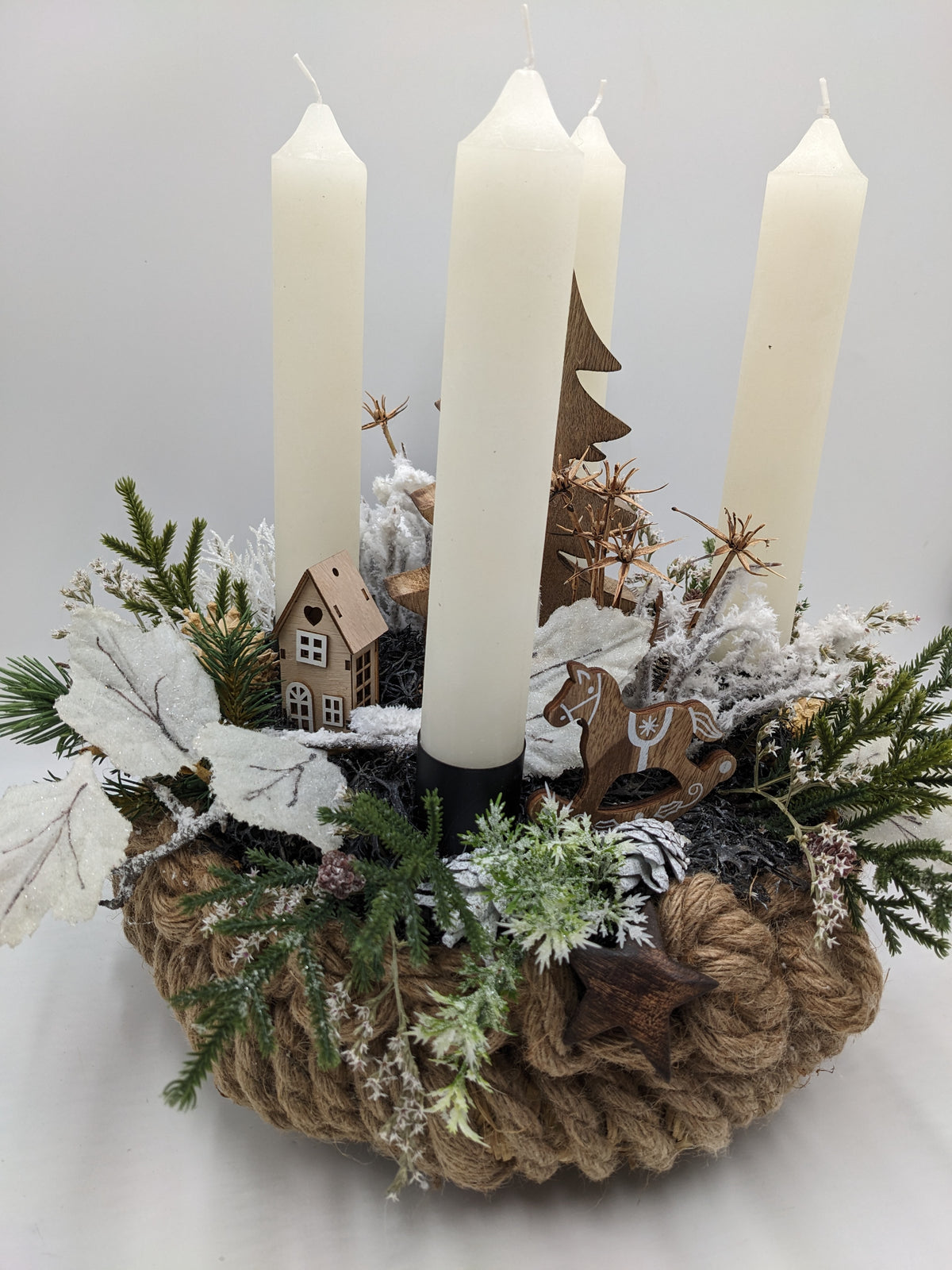 Adventsgesteck von der Seite: Naturseil-Schale, vier cremefarbene Stabkerzen, Tannenzweige und Holzstern