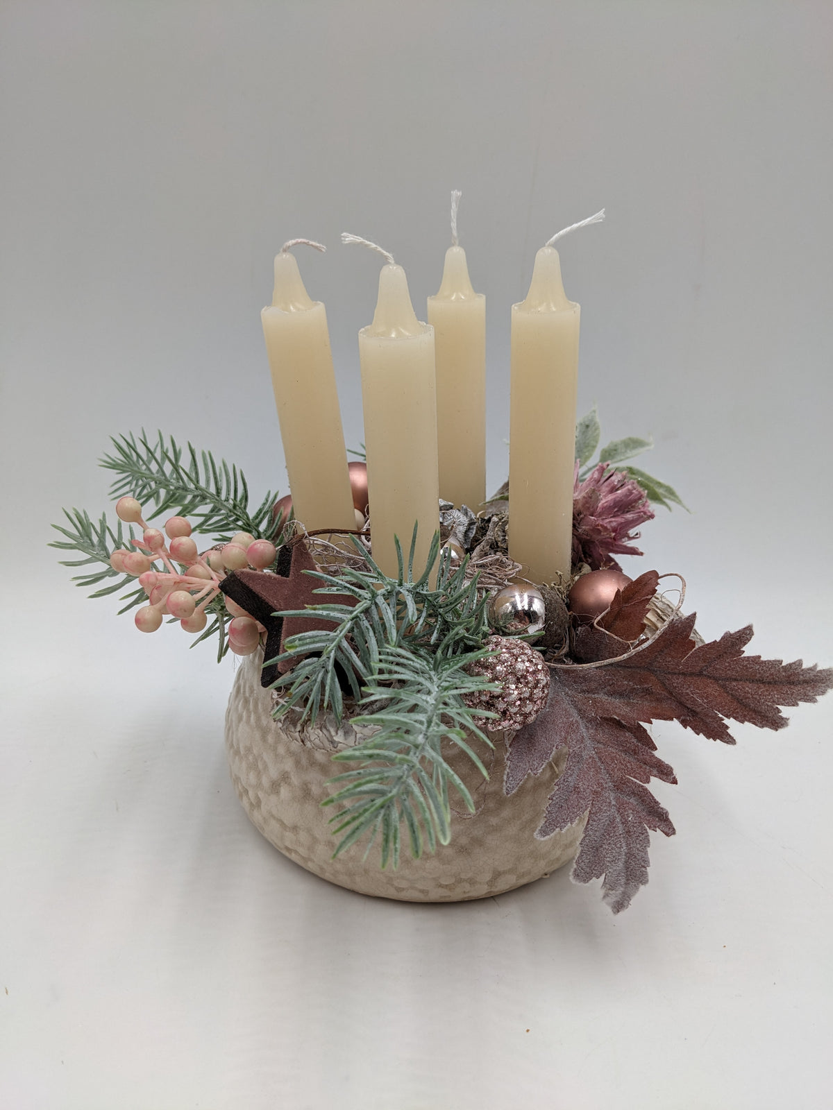 Adventsgesteck mit vier cremefarbenen Kerzen, rosa Beeren, Holzstern und Tannenzweigen in heller Keramikschale