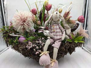Ostergesteck im Wurzelnest mit Stoffhase, rosa Tulpen, cremefarbener Distelkugel, Eiern und Beerenzweigen