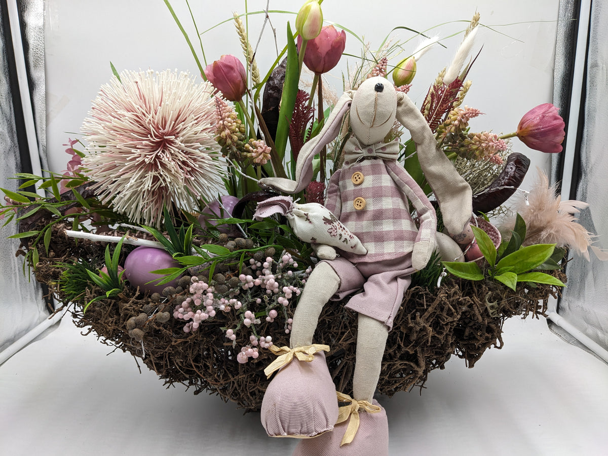 Ostergesteck im Wurzelnest mit Stoffhase, rosa Tulpen, cremefarbener Distelkugel, Eiern und Beerenzweigen