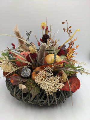 Herbstgesteck auf Weidenkranz mit Kürbis, rotem Apfel, Hagebutten, Zapfen und hellen Pampasgräsern