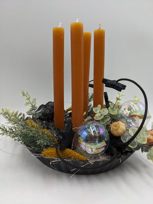 Adventsgesteck in schwarzer Backform mit ockerfarbenen Kerzen, Gräsern, Tannenzweigen und Metallbogen