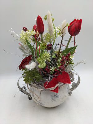 Frühlingsgesteck mit roten Tulpen, weißen Federgräsern und roten Beeren in weißem Kännchen mit Filzherz