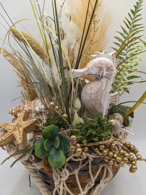 Detail des Sommergestecks: weiß gekalktes Seepferdchen, goldener Seestern, Sukkulente und goldene Beeren