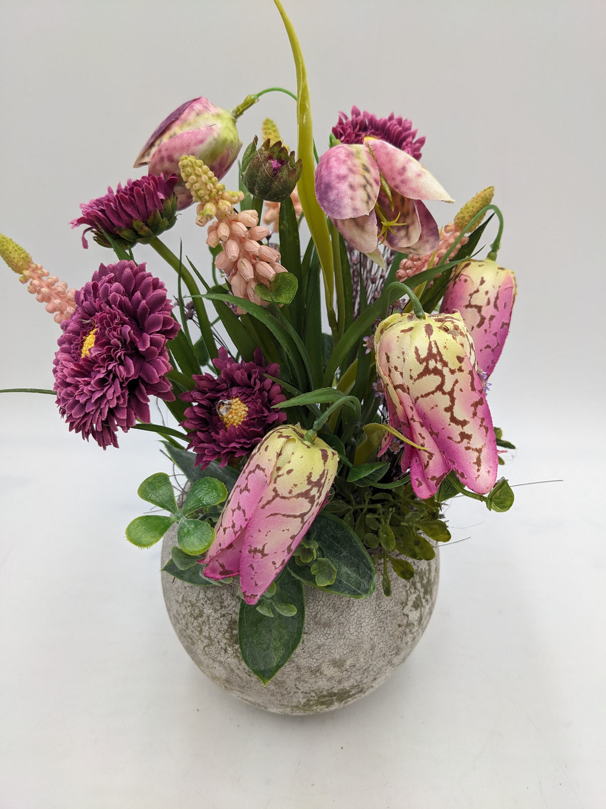 Gesteck von oben: gefüllte beerenfarbene Bellis, gefleckte rosa Schachbrettblumen und zartrosa Hyazinthen
