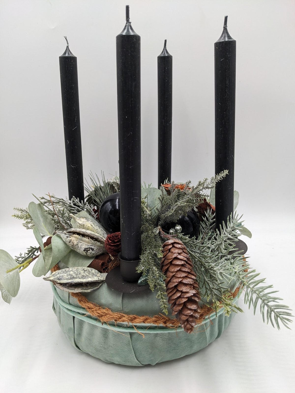 Adventskranz in mintgrüner Schale mit vier schwarzen Stabkerzen, Zapfen, Eukalyptus und Tannenzweigen