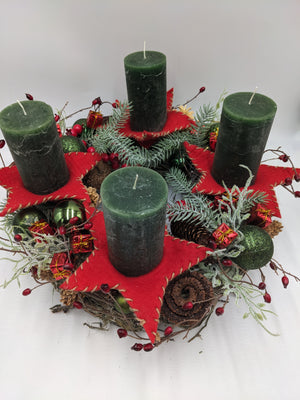 Adventskranz von oben: vier grüne Kerzen, rote Filzsterne, Tannenzweige, kleine rote Päckchen und Zapfenrosen