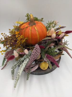 Herbstgesteck von oben: Kürbis in der Mitte, gelbe und weinrote Äpfel, Herbstlaub und pinke Heide