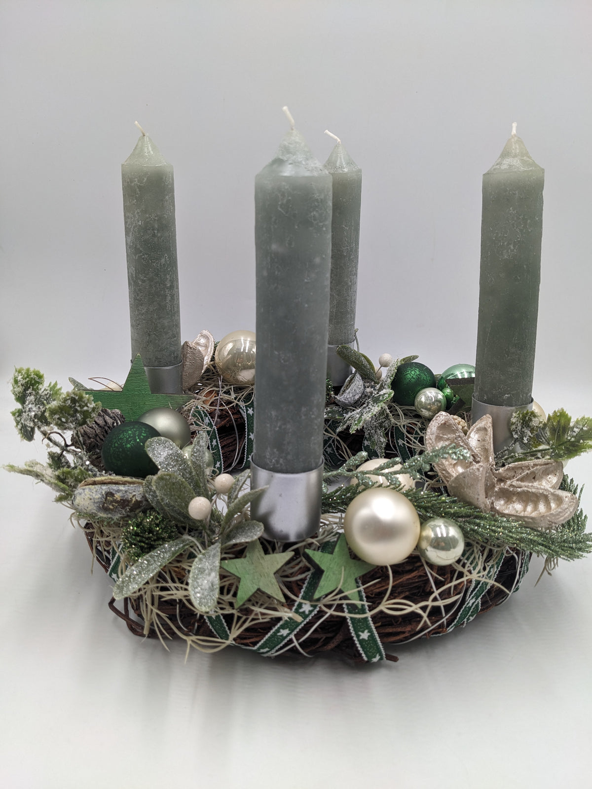 Adventskranz mit vier graugrünen Stabkerzen, cremefarbenen und grünen Kugeln, Misteln und Holzsternen
