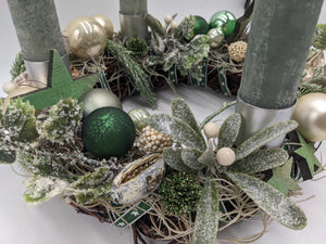 Nahaufnahme des Adventskranzes: dunkelgrüne Kugel, beschneite Mistelzweige mit weißen Beeren und grüner Holzstern