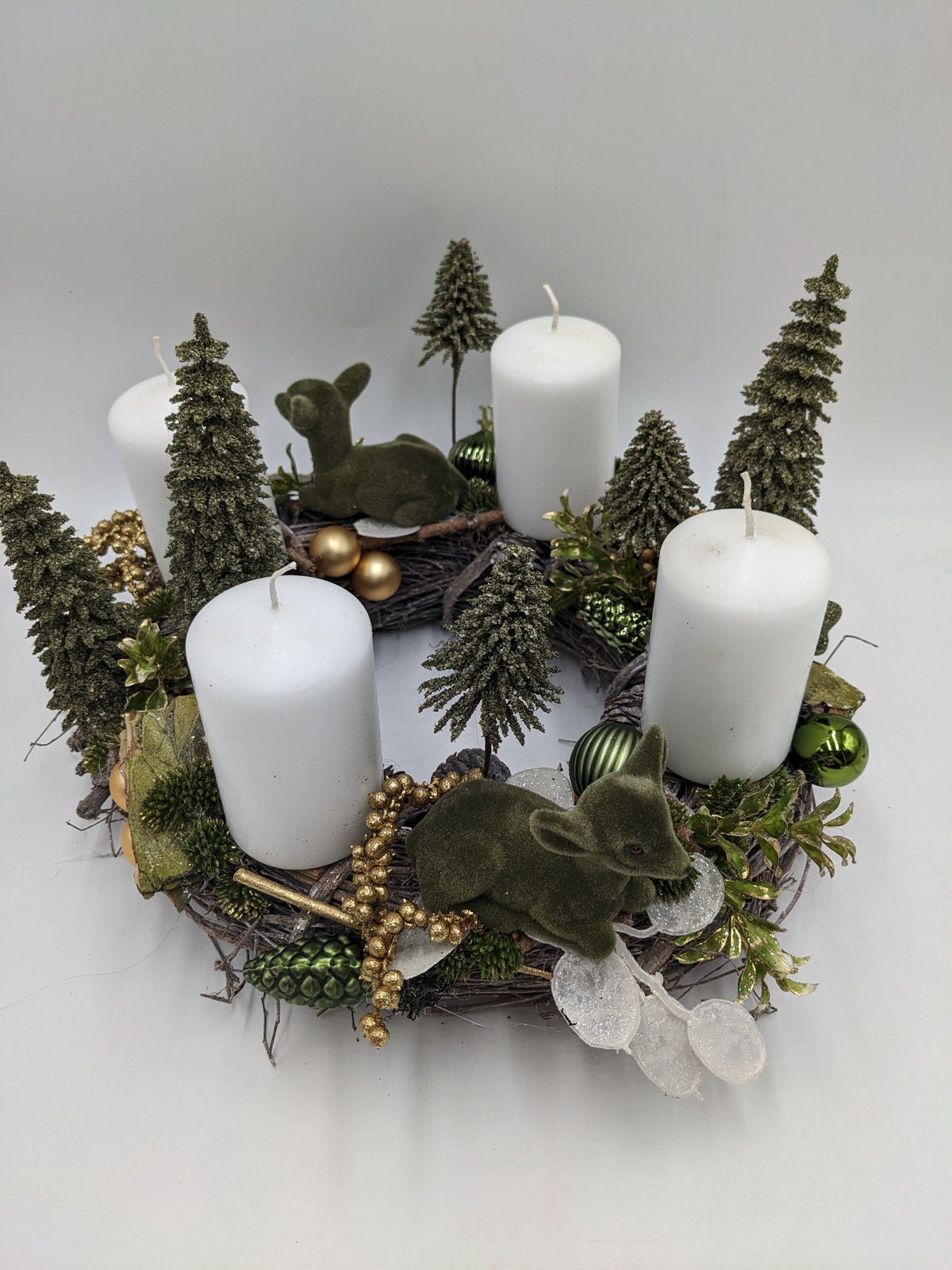 Adventskranz von oben mit vier weißen Stumpenkerzen, zwei grünen Rehkitzen, grünen und goldenen Kugeln