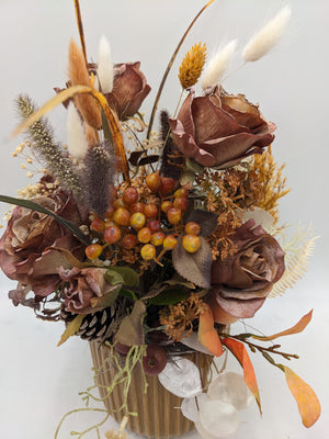 Nahaufnahme des Herbstgestecks: braune Rosen, orange-gelbe Beerendolde, helle Gräser und Silberblatt-Scheiben