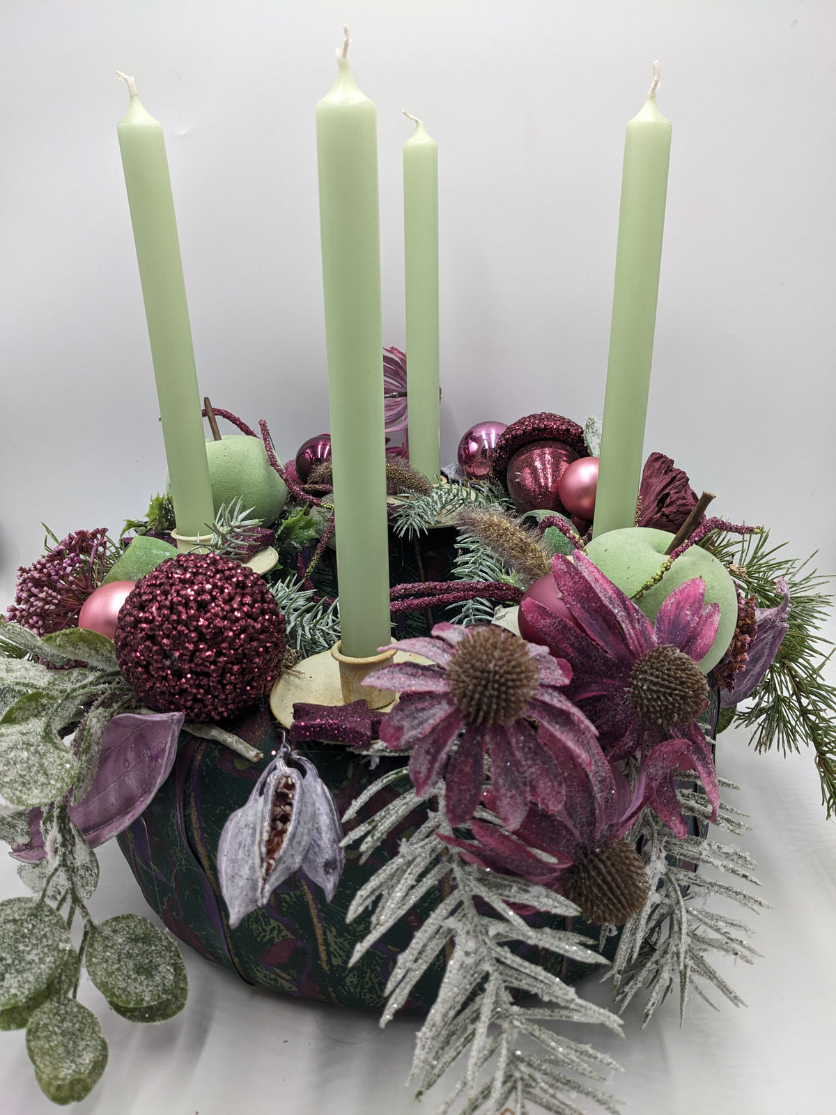 Adventskranz in Lila und Grün mit vier hellgrünen Stabkerzen, Beerenkugeln, Sonnenhut und grünen Äpfeln