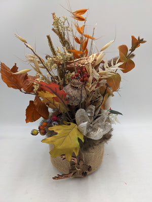 Herbstgesteck im Jutetopf mit kupferfarbenem Vogel, orangen Gräsern, Herbstlaub und roten Beeren