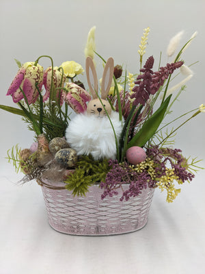 Ostergesteck mit Holzhase, rosa Schachbrettblumen, Hyazinthen und Wachteleiern in ovalem rosa Metallgefäß