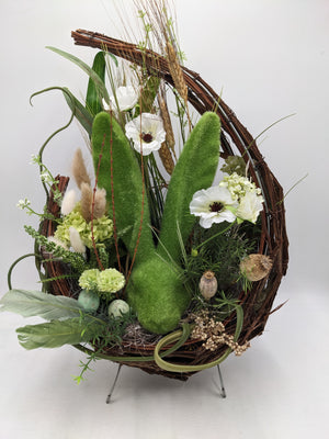 Ostergesteck im Rebenring mit moosgrüner Hasenfigur, weißen Mohnblüten, Gräsern und Getreideähren