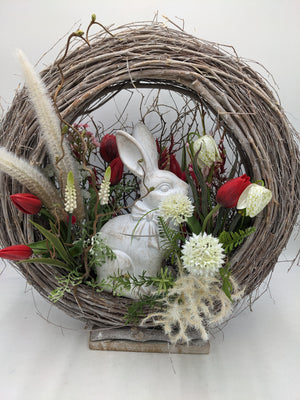Ostergesteck im Rebenkranz mit weißer Hasenfigur, roten Tulpen und weißen Blüten, Nahaufnahme