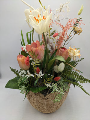 Frühlingsgesteck von oben: offene creme Tulpe, lachsrosa Tulpen, gelbe Narzissen und Farnwedel im Korb