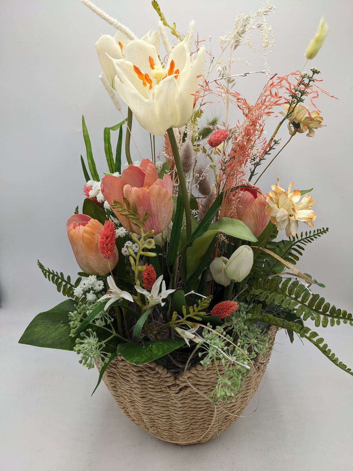 Frühlingsgesteck von oben: offene creme Tulpe, lachsrosa Tulpen, gelbe Narzissen und Farnwedel im Korb
