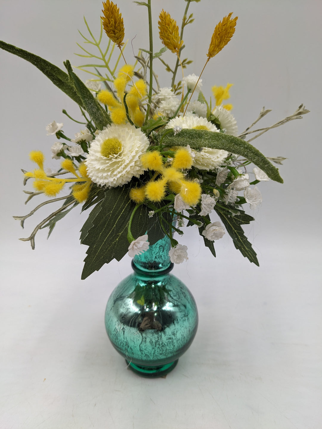 Frühlingsgesteck Vase Gräser Bellis türkis gelb