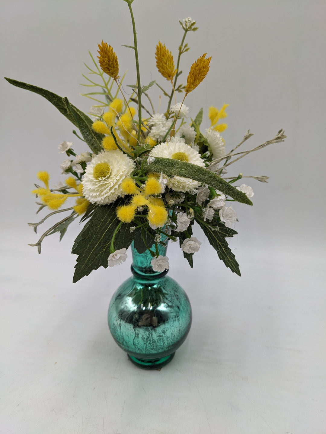 Frühlingsgesteck Vase Gräser Bellis türkis gelb