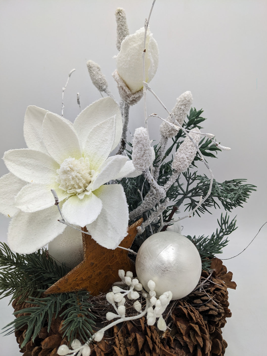 Weihnachtsgesteck Magnolie Zapfen Stern beschneit