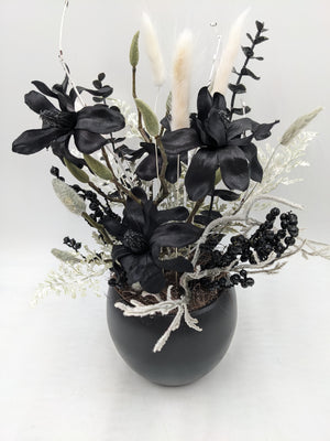 Nahansicht des schwarz-weißen Gestecks mit drei Magnolienblüten, bereiften Zweigen und Beerenrispen
