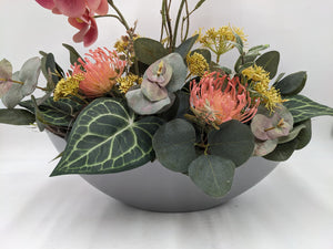 Nahaufnahme der Schale mit lachsfarbenen Nadelkissenblüten, gelben Dolden und grünen Eukalyptusblättern