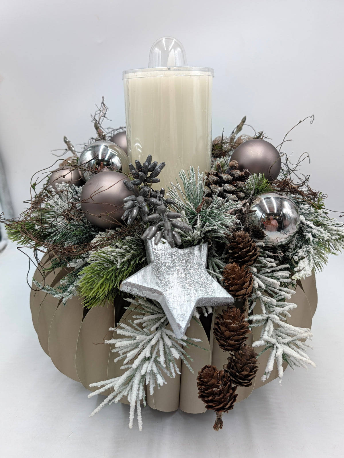 Adventskranz mit cremeweißer Kerze, taupefarbenen und silbernen Kugeln, Zapfen und Stern auf runder Schale