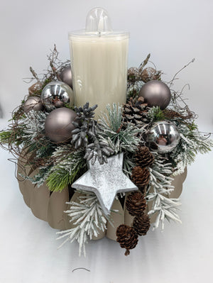 Adventskranz von vorn: silberner Holzstern, beschneite Zweige und Zapfenkette fallen über die taupefarbene Schale